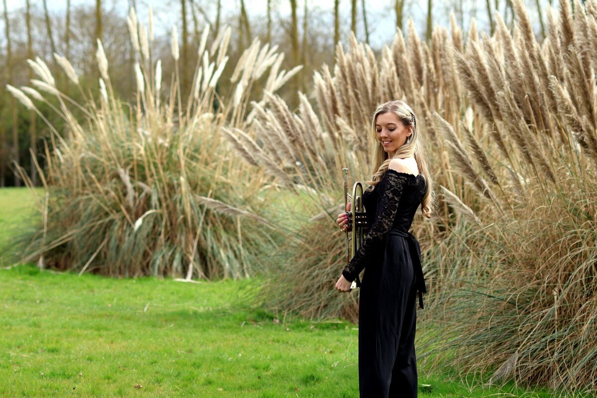 Jem Andrews with a trumpet near tall grasses